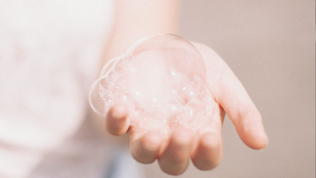 main contenant des bulles de savon ou de désinfectant utilisé avant une pigmentation